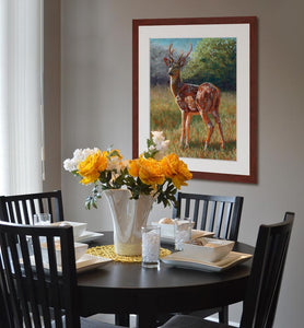 Pastel portrait print of a chital deer in the bright morning sun with a mahogany frame and 2” white mat hanging in a casual dining room.  Rendered in a contemporary style using bold strokes and bright colors by award winning artist Kathie Miller.