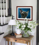 Pastel portrait print of a Siamese kitten with a mahogany frame and 2” white mat hanging on a stairs landing nook.  Rendered in a realistic style by award winning artist Kathie Miller.