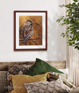 Pastel painting print of a house sparrow on gold leaf with a mahogany frame and 2” white mat hanging in a natural elements bedroom.  Rendered in a realistic style by award winning artist Kathie Miller.