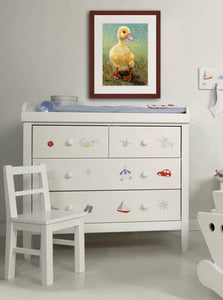 A mock up photo of a babies room. Hung on the wall is a print of my painting “Daisy-Duckling” by award winning artist Kathie Miller. The print has a mahogany frame and white mat. This is a contemporary pastel portrait of a little yellow duckling rendered in bold expressive strokes and bright colors. 