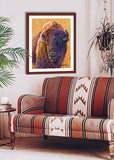 Pastel portrait print of a bison in the morning light with a mahogany frame and 2” white mat hanging in a western style living room. Rendered in a contemporary style using bold strokes and bright colors by award winning artist Kathie Miller. 
