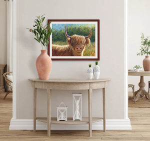 Pastel portrait print of a Highland cow in the morning sun with a mahogany frame and 2” white mat hanging in a elegant entrance hall. Rendered in a contemporary style using bold strokes and bright colors by award winning artist Kathie Miller. 