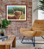 Pastel portrait print of a Highland cow in the morning sun with a mahogany frame and 2” white mat hanging in a western style living room. Rendered in a contemporary style using bold strokes and bright colors by award winning artist Kathie Miller. 