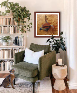 Pastel portrait print of a hooded golden eagle with a mahogany frame and 2” white mat hanging in a sitting corner of a living room. Rendered in a contemporary style using bold strokes and bright colors by award winning artist Kathie Miller. 