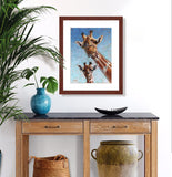 Pastel portrait of a young giraffe and his mother. Print with mahogany frame and a 2” white mat hanging in an entrance hall.  Rendered in a contemporary style using bold strokes and bright colors by award winning artist Kathie Miller.
