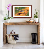 Pastel painting of a greater roadrunner in full run framed in mahogany and a white mat  hanging in an entrance hall.  Rendered in a contemporary style using bold strokes and bright colors by award winning artist Kathie Miller.