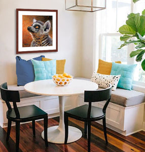 Pastel portrait print of a ring-tail lemur framed in mahogany and a white mat  hanging in a kitchen nook.  Rendered in a contemporary style using bold strokes and bright colors by award winning artist Kathie Miller.