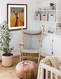 A mock up photo of a babies room. Hung on the wall is a print of my painting “Lilly – Deer Fawn” by award winning artist Kathie Miller. The print has a mahogany frame and white mat. This is a contemporary pastel portrait of a deer fawn rendered in bold expressive strokes and bright colors. 