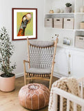 A mock up photo of a babies room. Hung on the wall is a print of my painting “Lucy-Goose” by award winning artist Kathie Miller. The print has a mahogany frame and white mat. This is a contemporary pastel portrait of a goose rendered in bold expressive strokes and bright colors. 
