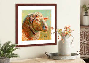Pastel portrait print of a sheep in the morning sun with a mahogany frame and 2” white mat hanging in a county kitchen. Rendered in a contemporary style using bold strokes and bright colors by award winning artist Kathie Miller. 