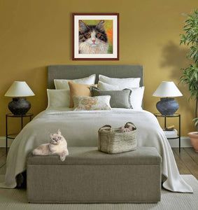 Pastel portrait print of a calico cat with a mahogany frame and 2” white mat hanging in an elegant bed room. Rendered in a contemporary style using bold strokes and bright colors by award winning artist Kathie Miller. 