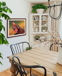 Pastel portrait print of a Welsummer hen with a mahogany frame and 2” white mat hanging in a country dining room. Rendered in a contemporary style using bold strokes and bright colors by award winning artist Kathie Miller. 