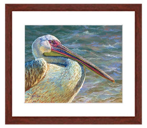 Pastel portrait of a pelican with the ocean in the background. Print with a mahogany frame and 2” white mat. Rendered in a contemporary style using bold strokes and bright colors by award winning artist Kathie Miller. 