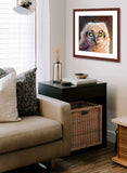 Pastel portrait print of a fluffy great horned owl chick with a mahogany frame and 2” white mat hanging in a living room corner. Rendered in a contemporary style using bold strokes and bright colors by award winning artist Kathie Miller. 