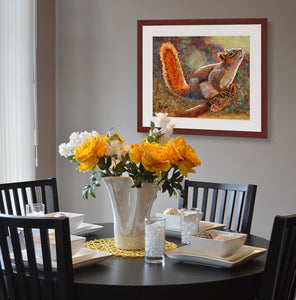 A mock up photo of a simple dining area. Hung on the wall is a print of my painting “Rocky-Squirrel” by award winning artist Kathie Miller. The print has a mahogany frame and white mat. This is a contemporary pastel portrait of a squirrel rendered in bold expressive strokes and bright colors. 