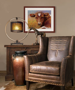 Pastel portrait print of a longhorn calf with a perfect heart on her forehead laying in the sun framed in mahogany and a white mat  in western style sitting area.  Rendered in a contemporary style using bold strokes and bright colors by award winning artist Kathie Miller.