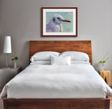 A mock up photo of an elegant bedroom. Hung on the wall is a print of my painting “Waiting for the Boats to Come In – Sea Gull” by award winning artist Kathie Miller. The print has a mahogany frame and white mat. This is a contemporary pastel portrait of a sea gull rendered in bold expressive strokes and bright colors. 
