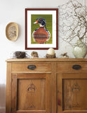 Pastel portrait of a wood duck rendered in a photo realistic style with a mahogany frame hanging over an antique credenza by award winning artist Kathie Miller.