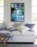 Abstract painting of a waterfall in blues and greens with a mahogany frame hanging in an elegant living room with blue accents by award winning artist Kathie Miller